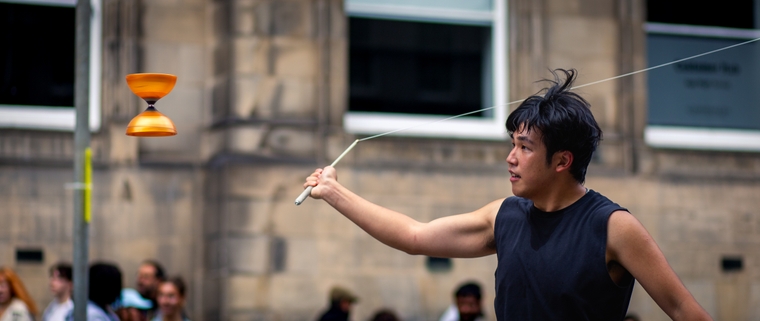 The diabolo frozen in the air as the string orbits, journeying to ensnare it