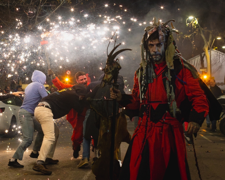 An ominous character stares down the camera while behind people gather under a sparkler